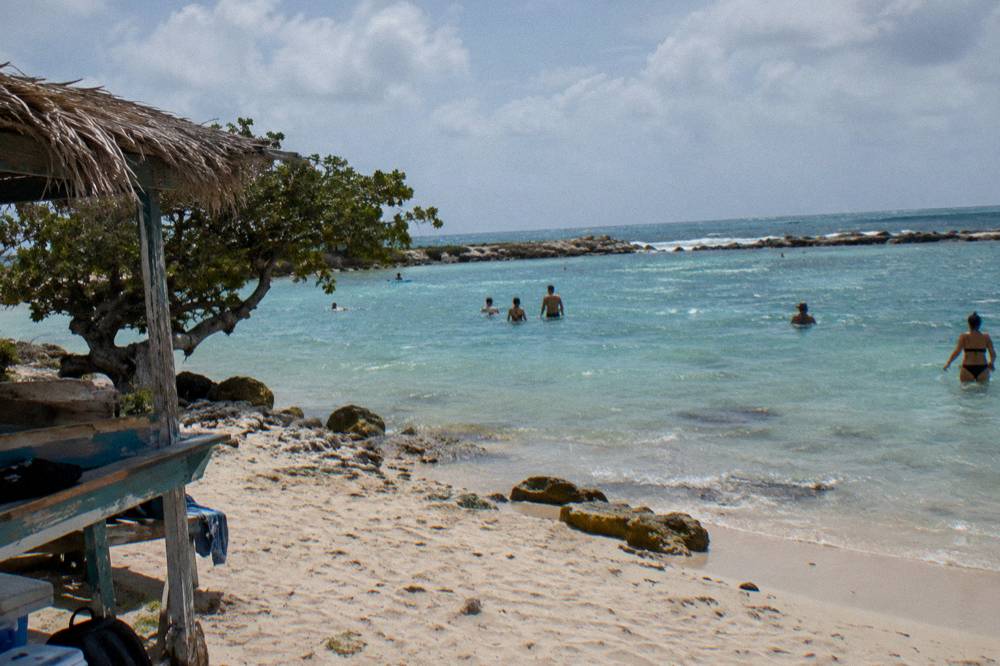 A calm sandy beach with shallow clear water at the island's south tip